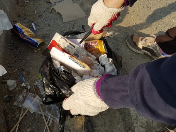 단속반들이 불법 투기한 쓰레기에서 증거물을 찾고 있다. 배달영수증, 전기․수도․가스요금 고지서를 통해 투기자를 적발할 수 있다.