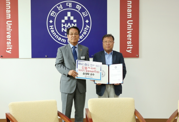 한남대 손대락 교수(오른쪽)가 1억원 이상 발전기금 기탁자에게 부여하는 아너스클럽 멤버 인증서를 이덕훈 총장에게 전달받고 있다.