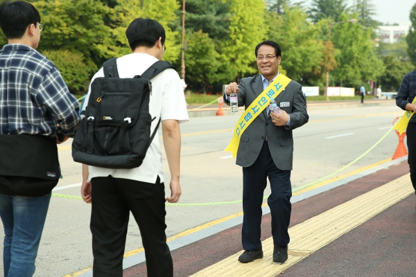 한남대 이덕훈 총장이 등교하는 학생에게 생수를 나눠주며 반갑게 인사하고 있다.
