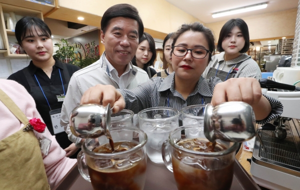 황인호 구청장이 일자리 현장을 찾아 커피 만드는 모습을 지켜보고 있다