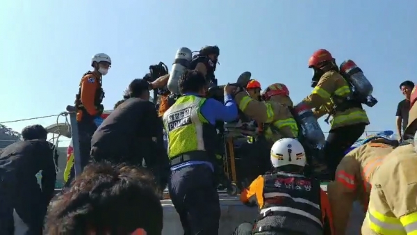 해경과 소방이 질식선원을 구조해 육상 대기중인 119로 옮기고 있다