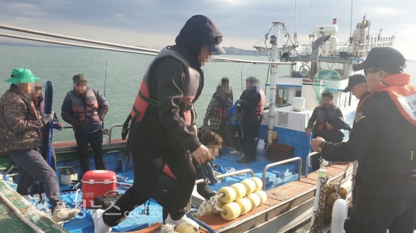 해경이 기관 고장으로 표류하던 낚싯배의 낚시승객들을 경비함정으로 이동시키고 있다.