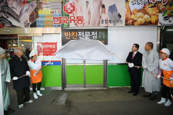 황선봉 군수(오른쪽에서 세번째)와 관계자들이 시니어클럽 시장형사업단 시니어 COOK 개소식에서 간판 제막을 하는 모습