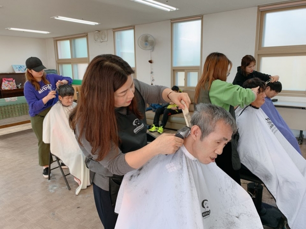 미용봉사 중인 손지연 학과장(중앙)과 재학생들 모습