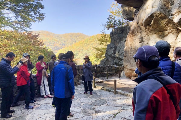 서산용현리마애여래삼존상을 방문한 단체관광객들이 해설사의 설명을 듣고 있다.