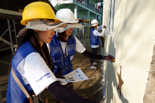 해외봉사단이 미얀마 현지에서 건물 외벽 페인팅     봉사활동을 펼치고 있는 모습