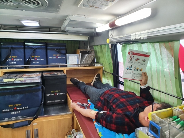 헌혈버스에서 헌혈을 하면서 주의사항을 읽고 있는 모습