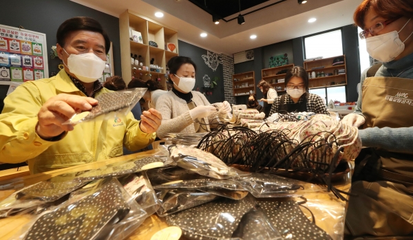 황인호 동구청장이 마을살림공작소 직원들과 함께 면마스크 포장을 하고 있다