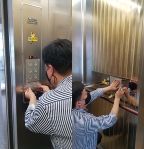 동구청 직원이 공동주택 엘리베이터에 코로나19 항균필름을 부착하고 있다.