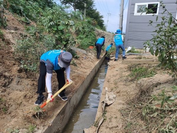 공사 직원들이 수로에 있는 토사물을 제거하고 있다.