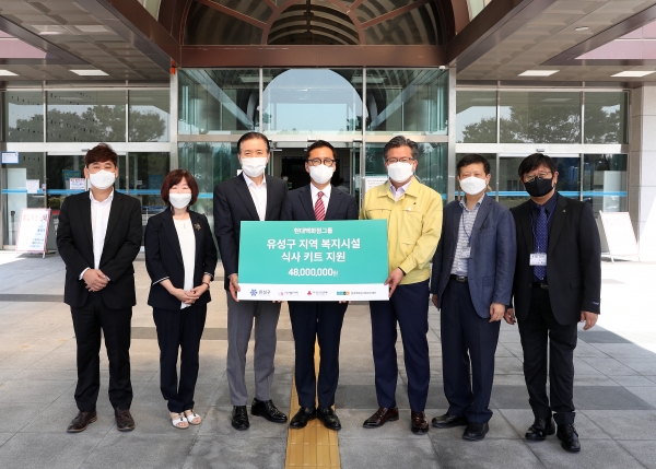 15일 구청 본관 입구에서 최정규 점장(가운데)이 정용래 유성구청장(오른쪽에서 세 번째)과 신동천 유성구행복누리재단 상임이사(왼쪽에서 세 번째)에게 취약계층 지원을 위한 4,800만 원 상당의 후원물품을 기탁하고 있다