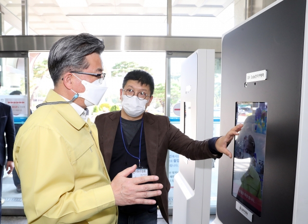 19일 정용래 유성구청장(왼쪽)이 구 청사 출입구에 설치된 스마트 출입관리시스템을 시연하며 이상훈 대표(오른쪽)의 설명을 듣고 있다