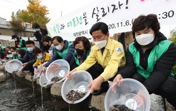황인호 동구청장과 행사 참여자들이 대동천에 미꾸라지를 방류하고 있다.