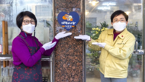 박정현 대덕구청장이 법동 ‘크라운꽃집’에 대덕e나눔 참여점포 지정 현판을 부착하고 있다