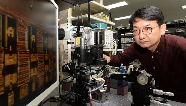 ETRI 한영탁 책임연구원이 400G 광학송수신엔진에 사용된 반도체 광원 칩 살펴보고 있는 모습.