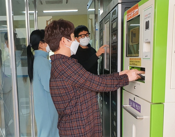 도서 대여자들이 새로 설치된 자동도서반납기를 이용해 도서를 반납하는 장면