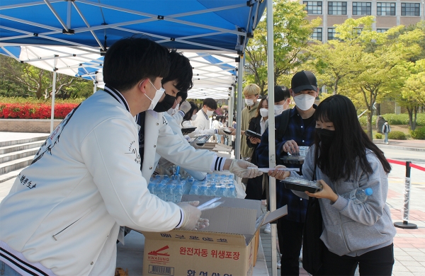 21일 정오 목원대학교 중앙도서관 광장에서 총학생회 관계자들(왼쪽)이 학생들에게 도시락을 전하고 있다.