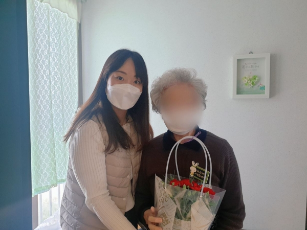 아산시치매안심센터 직원이 치매어르신에게 카네이션 화분을 전달하고 있다