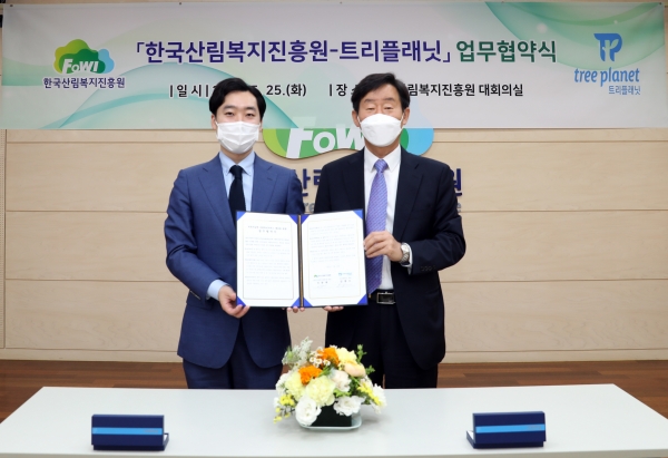 이창재(오른쪽) 한국산림복지진흥원장이 25일 한국산림복지진흥원 본원 대회의실에서 김형수 트리플래닛 대표와 업무협약서를 들고 기념촬영을 하고 있다