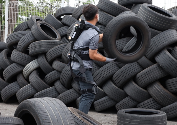 근력지원을 받으며 타이어 적재 작업을 수행하는 근로자