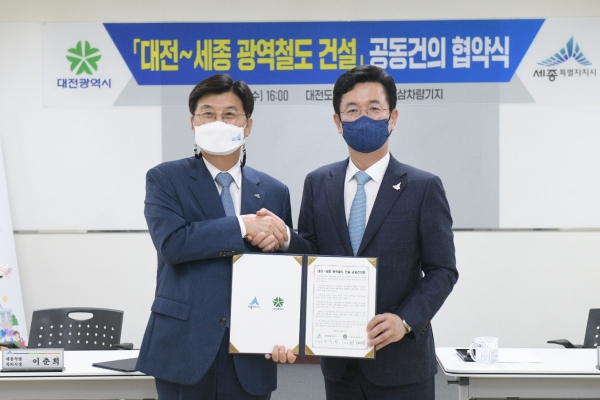 허태정 대전시장과 이춘희 세종시장이 7일 대전-세종 광역철도 건설 공동건의문에 서명 후 악수하고 있다.