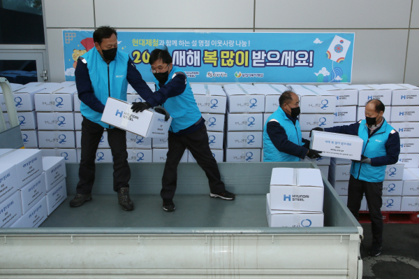 현대제철 당진제철소 임직원 봉사자가 설 선물세트를 비대면 드라이브스루형태로 차량에 싣어주고 있는 모습