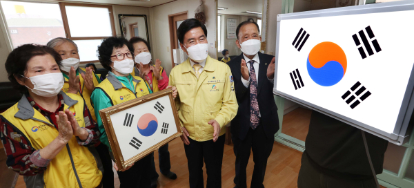 황인호 동구청장(사진 왼쪽 다섯 번째)과 박헌철 대한노인회 대전광역시 동구지회장(사진 왼쪽 여섯 번째), 경로당 회원들이 설치 중인 LED태극기를 살펴보고 있다.