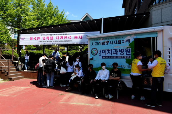 이손의료재단의 치과진료차량 앞에 유학생들이 줄을 서 순서를 기다리고 있다.