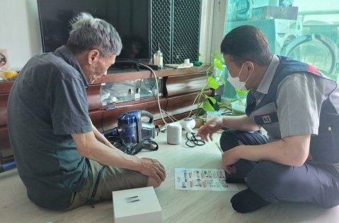 새롭게 선정된 돌봄서비스 대상자에게 인공지능(AI) 스피커 설치 후 사용법을 설명하고 있다