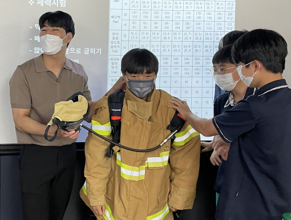대전버드내중학교에서 목원대 소방안전학과 대학생 멘토(왼쪽)가 중학생들의 소방안전장비 체험을 돕고 있다.