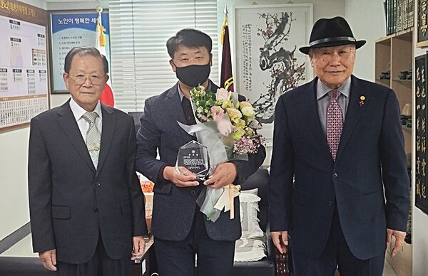 유홍준 대한노인회 천안시지회장(우)이 윤상원 환경정책과장(가운데)에게 감사패를 전달하고 기념사진을 찍고 있다.