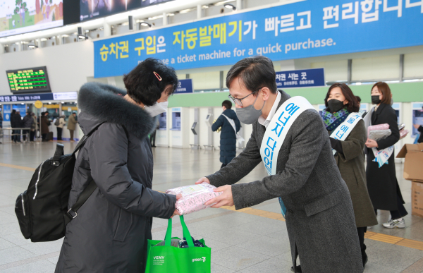 한국서부발전 직원들이 서울역 이용객에게 방한용품을 전달하는 모습