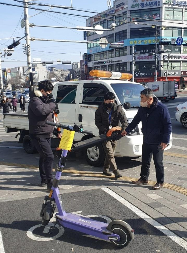 천안시 관계자가 보도 내 무단방치된 공유킥보드를 이동조치하고 있다.