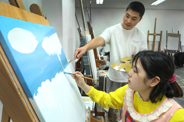 한남대 회화과 김지우씨(사진 앞)를 장애학생도우미 하서진씨가 도움을 주고 있다.