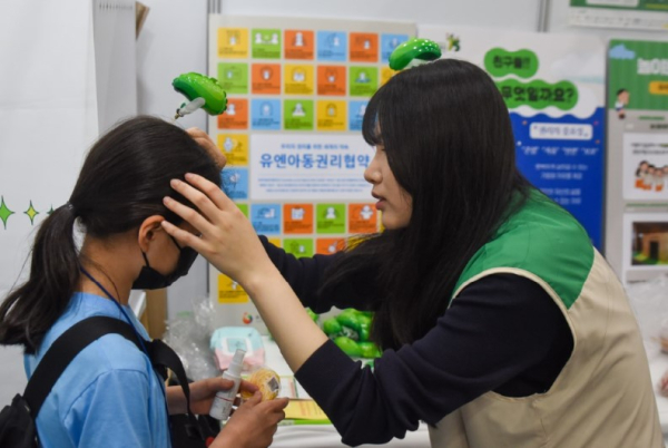 ‘제 3회 대한민국 어린이 대상’ 투표에 참여한 아동에게 초록우산 모양의 풍선머리핀을 제공하고 있다.