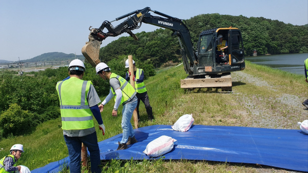 응급복구반과 긴급복구 동원업체가 임시 물길 조성 작업을 시현하고 있다
