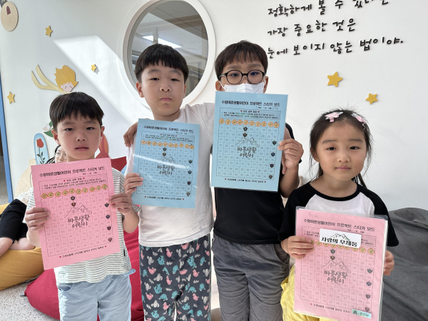 수왕초 학생들이 스티커 북을 들고 인증 사진을 찍고 있다.