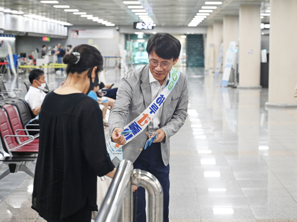 김선수 한국서부발전 여수건설본부장(오른쪽)이 공항 이용객에게 에너지 절약 안내문과 부채를 전달하고 있다.