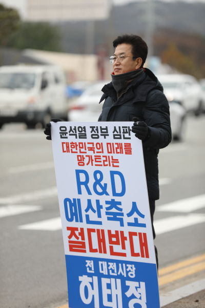허태정 전 시장이 대덕특구 인근에서 R&D 예산 축소 반대라는 문구가 담긴 피켓을 들고 시위를 벌이고 있다.