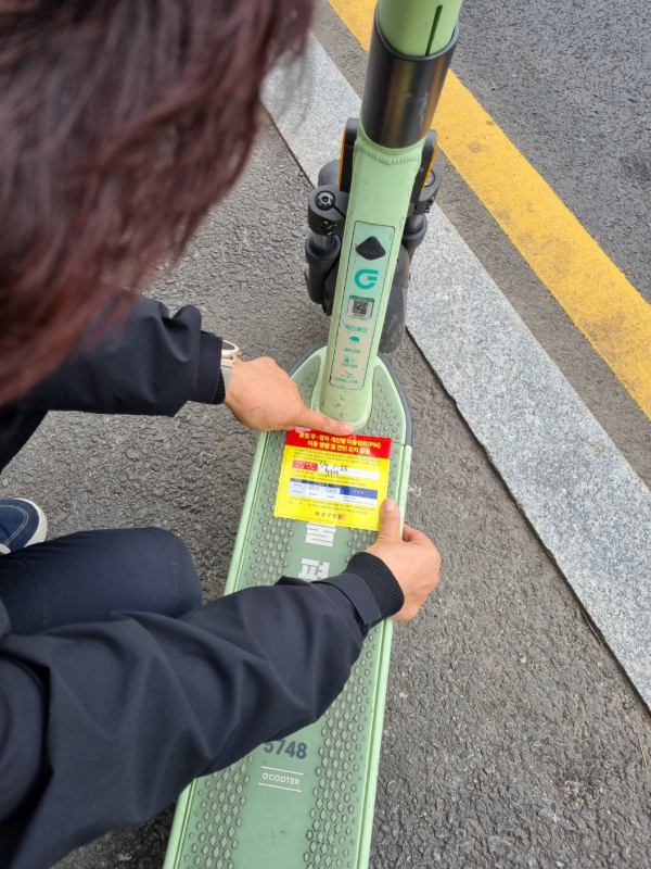 견인대행업체 직원이 무단 방치된 전동킥보드 이동 및 견인안내 부착을 하고 있다.