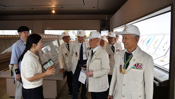 6.25. 참전용사 어르신들이 학예사의 설명을 들으며 화폐박물관 전시실을 관람하고 있다.