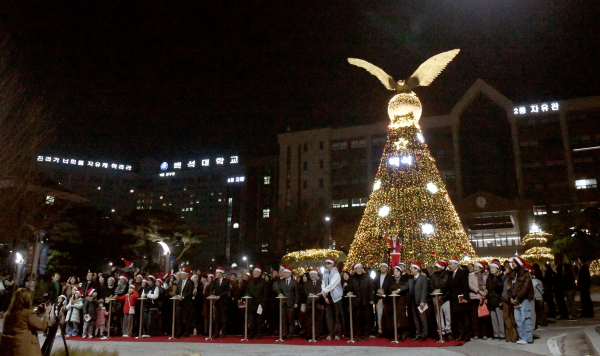 독수리탑 앞에서 크리스마스트리 점등식에 참여하고 있는 단체사진.