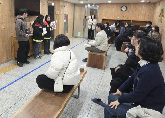 직원이 방문객에게 산불 예방 홍보 안내문을 전달하고 있다.