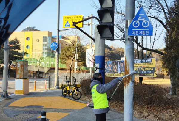 유성구청 직원이 어린이 보호구역 내의 불법광고물을 정비하고 있다.