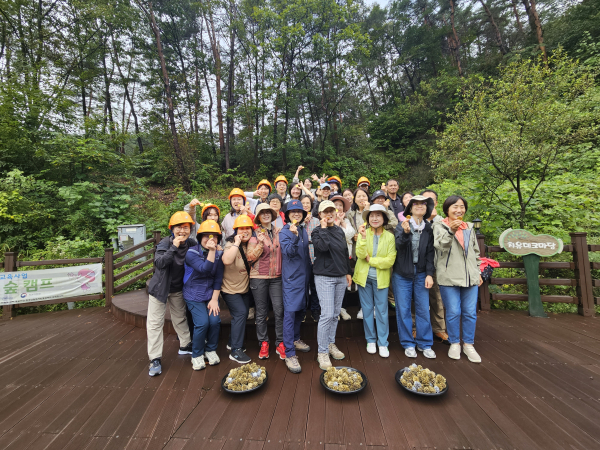 국립양평치유의숲 금광굴 앞에서 광부 모자를 쓴 프로그램 참여자들이 금광굴 황금열매를 앞에 두고 단체 사진 촬영