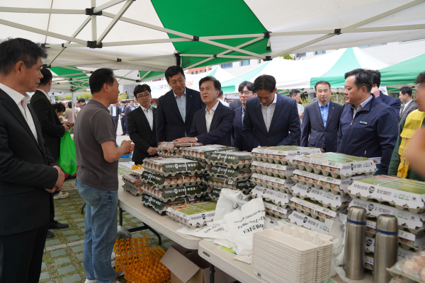 내포직거래장터에서 농산물을 살펴보며 상인과 이야기하는 사진