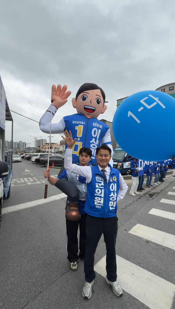이상민 후보의 아들이 커다란 인형을 업은 채 아버지와 함께 거리인사를 다니고 있다.