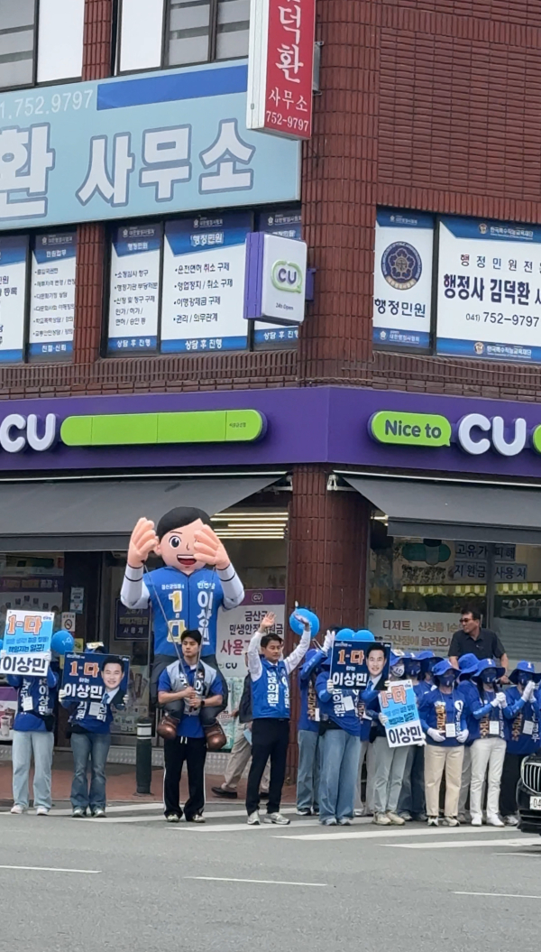 이상민 후보의 아들이 커다란 인형을 업은 채 아버지와 함께 거리인사를 다니고 있다.