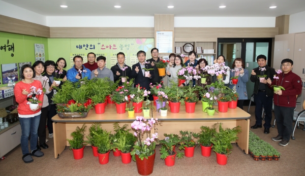 군 농업기술센터 직원들이 구입한 화분을 들고 있는 모습