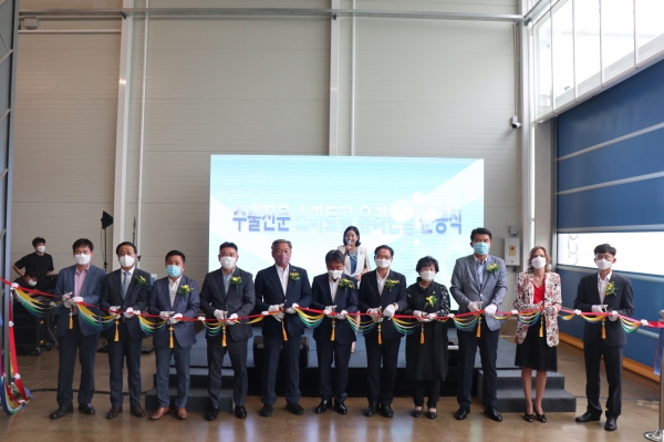 지난 24일 진행된 우듬지팜의 수출전문 스마트팜 첨단온실 준공식에서 우듬지팜 관계자들과 행사에 참석한 내빈들이 기념 테이프 커팅식을 진행하고 있다